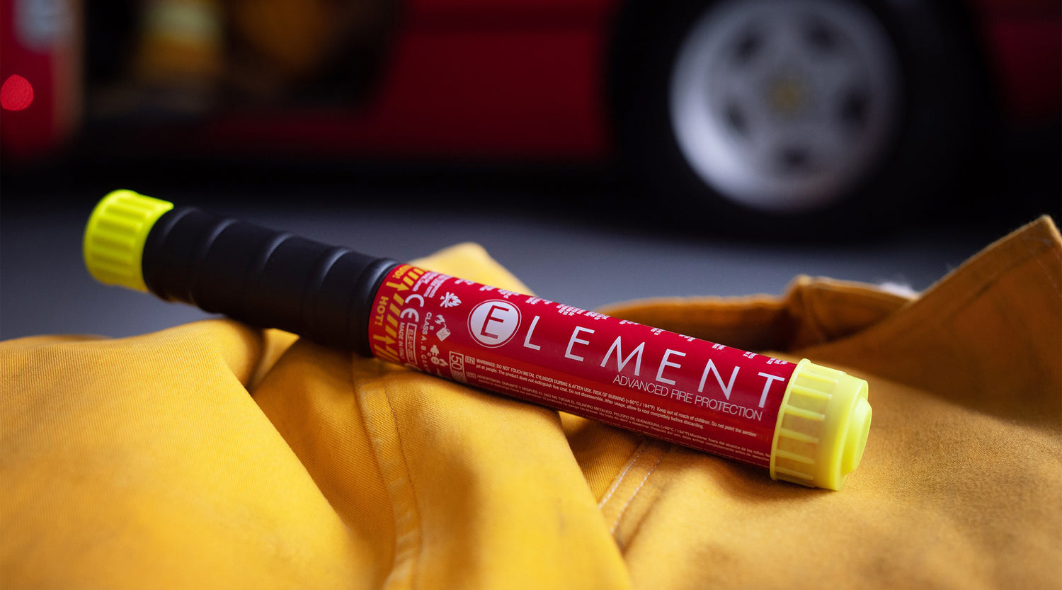 Extincteur Element posé sur un habit jaune dans un garage à voiture